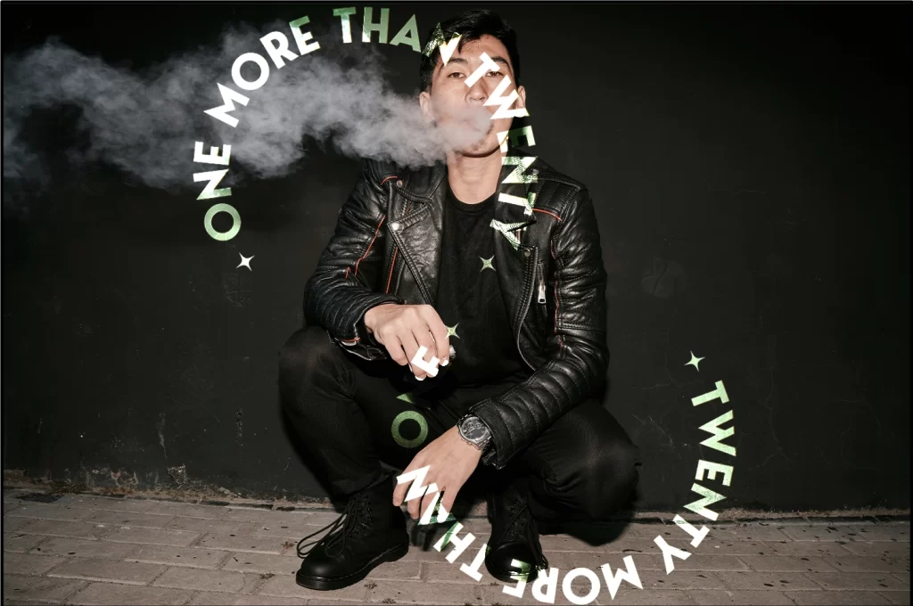 A man sitting on the floor, exhaling smoke